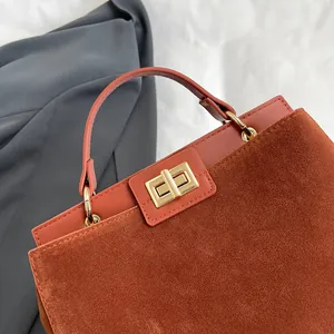 Vue détaillée du daim rouge rouille et du cuir lisse avec fermoir en métal doré