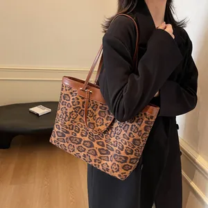 Detail shot of a large leopard print tote bag with brown leather handles worn on shoulder