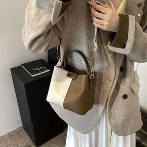 Detail shot of a two-tone bucket bag with lychee texture and detachable shoulder strap