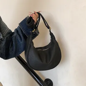 Détail du sac hobo en cuir noir avec anneaux dorés et bandoulière réglable