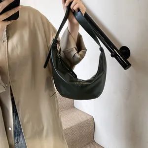 Detalle de un bolso hobo de cuero verde oscuro con correa ajustable y costuras