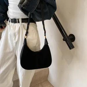 Détail du sac croissant en cuir noir avec ferrures dorées porté par un mannequin