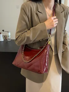 Elegant wine red quilted shoulder bag with gold chain strap on a blazer outfit