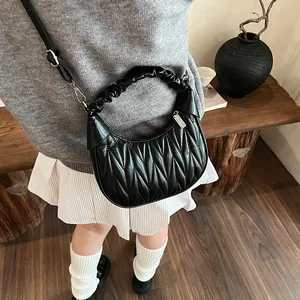 Detail view of black pleated cloud handbag with adjustable strap in minimalist setting