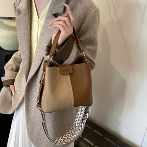 Detail of contrast stitching beige and brown bucket bag with chevron strap and embossed logo