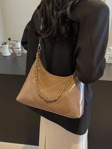 Brown quilted shoulder bag with gold chain strap worn by model in a café setting