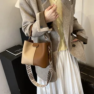 Chic two-tone bucket bag with wide geometric strap and brown leather contrast details