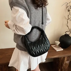 Detail of black quilted cloud handbag with ruched handle and detachable strap on model
