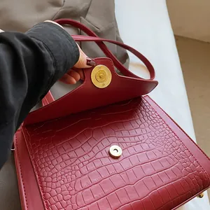 Close-up of deep red crocodile pattern leather handbag with gold magnetic closure details