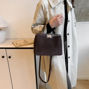 Détail du sac à main en daim marron foncé avec fermoir doré et poignée supérieure