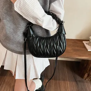 Detail view of black pleated crescent bag with V-shaped quilting and ruched handle