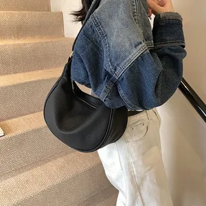 Détail du sac hobo noir en cuir à motif litchi avec fermeture éclair et bandoulière dorées