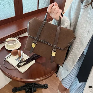 Detail shot of a vintage brown frosted suede handbag with golden metal buckles