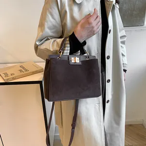 Vue détaillée du sac Kelly en daim marron foncé avec fermoir doré et bandoulière