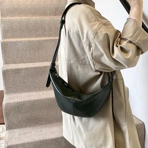 Modelo luciendo un bolso de hombro de media luna verde oscuro estilo moderno