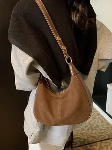 Sac hobo en daim marron avec rivets dorés réglables présenté sur un mannequin