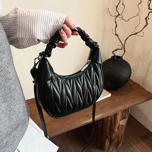 Detailed close-up of a black matelassé pleated leather hobo bag with a matching handle