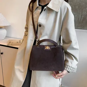 Détail du sac Kelly en cuir mat marron foncé avec boucle tournante dorée et bandoulière