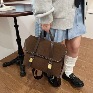 Detail of vintage brown suede messenger bag featuring gold buckle straps and carrying handle