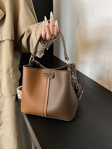 Elegant two-tone brown bucket bag with lychee texture and patterned shoulder strap