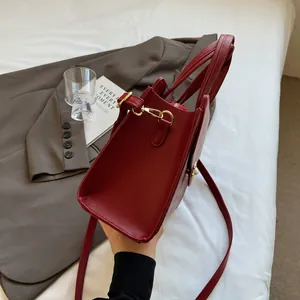 Detail of burgundy PU leather tote bag with gold hardware and pearl trim decoration