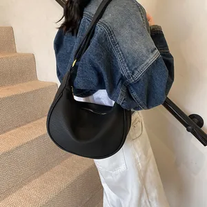 Détail d'un sac demi-lune noir en cuir grainé avec fermeture éclair métallique robuste