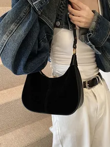 Sac hobo élégant en daim noir avec boucles dorées porté par un mannequin