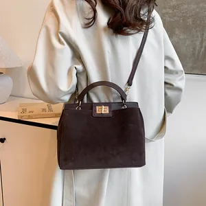 Détail du sac cabas marron foncé en daim mat avec un élégant fermoir en métal doré brillant