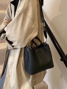 Black pebbled leather bucket bag with a stylish geometric woven shoulder strap for women