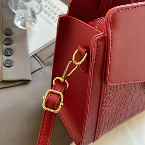 Macro detail of red crocodile embossed leather tote with gold-tone metal hardware
