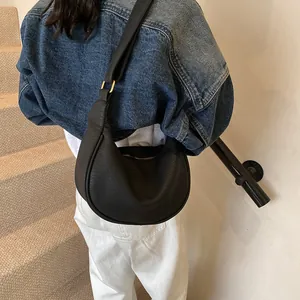 Gros plan du sac demi-lune noir en cuir grainé avec boucle de réglage en métal doré
