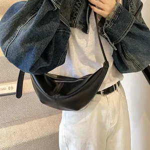 Detalle del bolso de media luna en cuero negro con textura suave y costura vertical