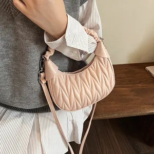 Detail view of pink pleated crescent bag showing the textured faux leather and metal clasp