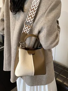Retro bucket bag in brown and white leather with a geometric patterned wide strap