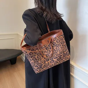 Detailed side view of large leopard print tote bag with brown leather handles on shoulder