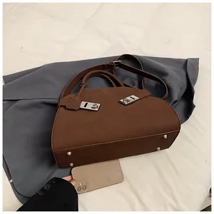 Deep brown tote bag detail showing bottom protective rivets and adjustable strap