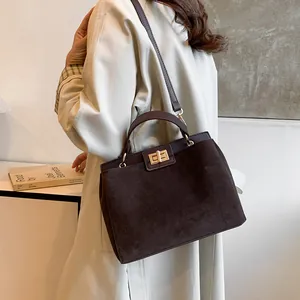 Détail du sac Kelly en daim marron foncé avec fermoir rotatif doré et une poignée