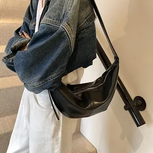Detalle de bolso medialuna negro en cuero sintético con textura y cremallera