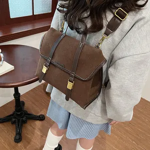 Detail of vintage coffee brown suede satchel with leather straps and gold metal buckles