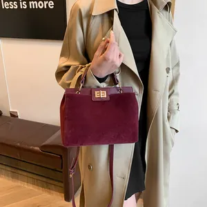 Détail du sac Kelly bordeaux avec texture en daim mat et fermoir rotatif doré élégant
