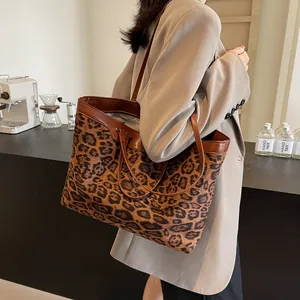 Detail of leopard print tote bag with brown leather straps shown on a model's shoulder