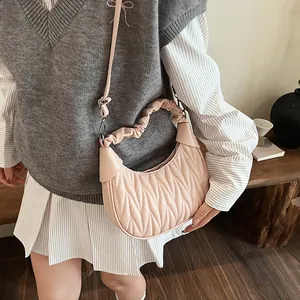 Detailed view of pink pleated half-moon bag with elegant quilted texture and silver hardware