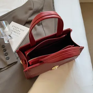 Detailed view of red leather tote bag showing double zipper pockets and golden buckle detail