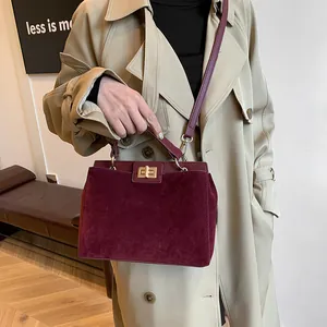 Gros plan détaillé du sac Kelly bordeaux en daim avec fermoir rotatif doré