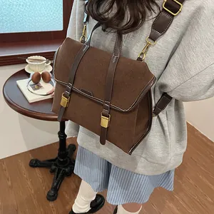 Detail view of deep brown suede backpack with vintage gold buckles and white stitching