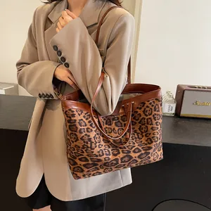 Close-up of leopard print tote bag featuring dual brown leather straps and detailed stitching