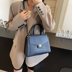 Detail of dark blue tote with crocodile texture, gold flower buckle and pearl accent