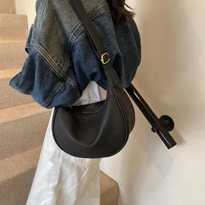 Vue détaillée du sac demi-lune noir plissé avec boucles dorées et bandoulière réglable