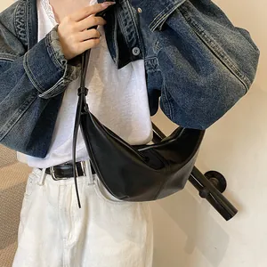 Detalle del bolso de media luna negro minimalista en modelo con chaqueta vaquera