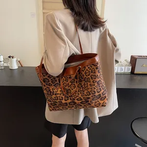 Detailed view of large leopard print tote bag worn on shoulder in a cozy cafe setting